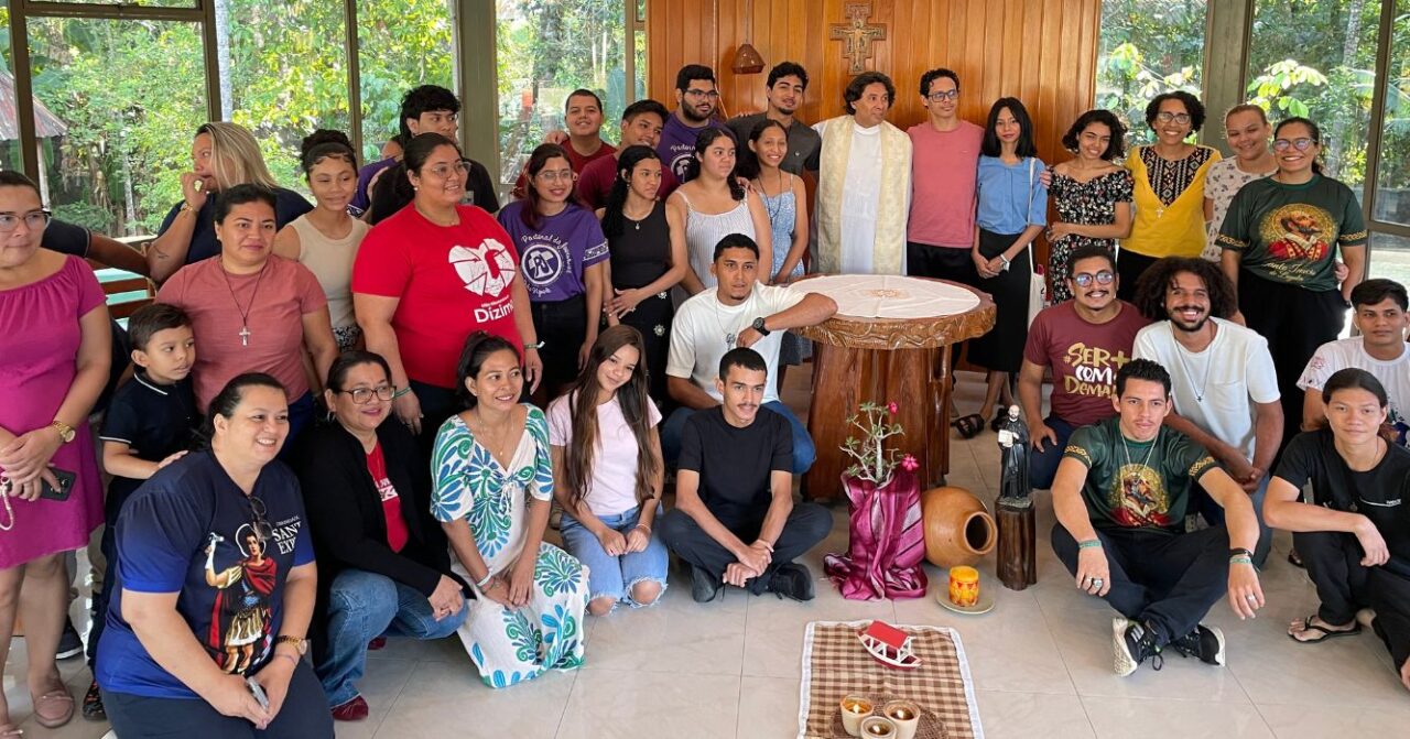 Grupo de jovens e adultos reunido ao redor do altar na Casa de Retiro Ir. Vicente de Cãnas, em Manaus (AM), durante os Exercícios Espirituais para Jovens (EEJ). Ao centro, um sacerdote aparece junto aos participantes após a celebração.