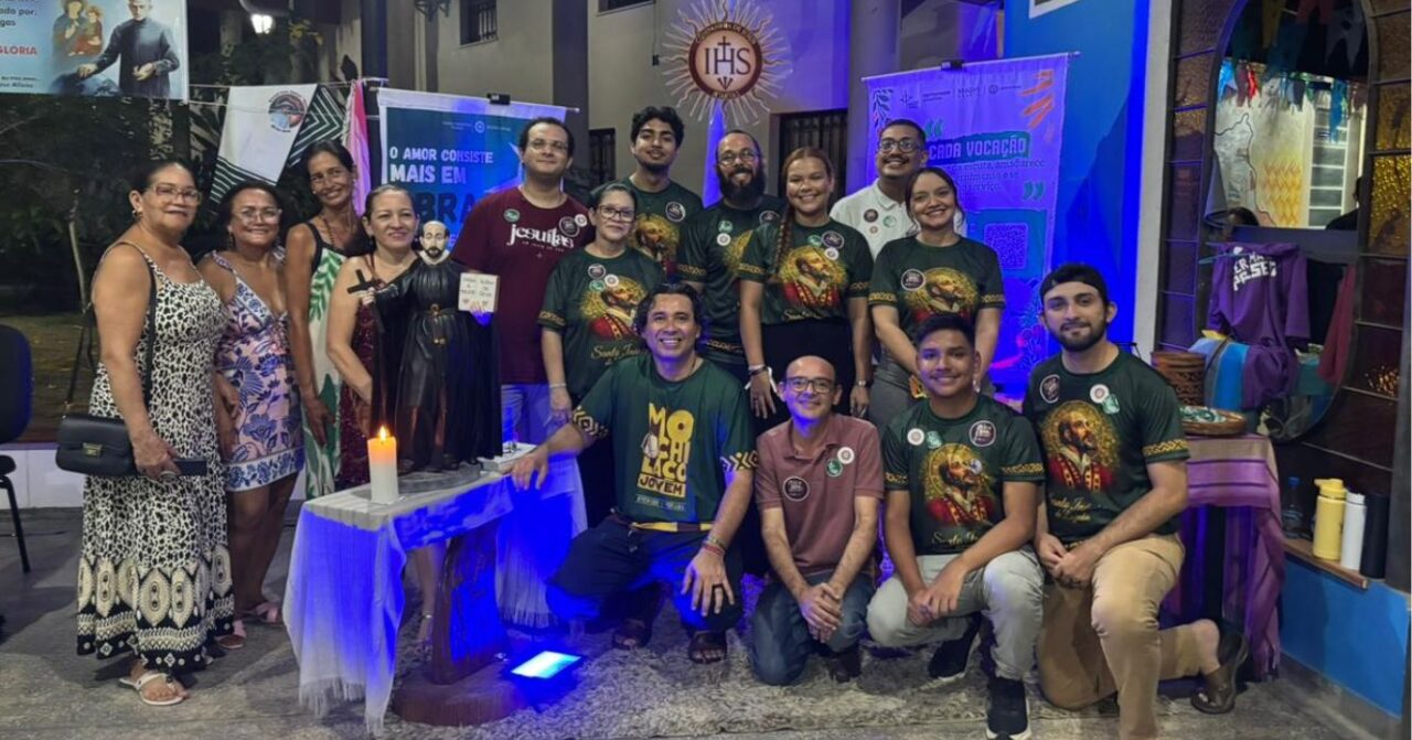 Jovens, religiosos e participantes reunidos junto à tenda da Companhia de Jesus durante a Feira Vocacional em Manaus (AM), com materiais sobre vocação, espiritualidade inaciana e missão jesuíta.
